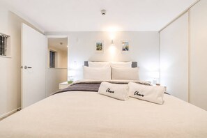Ein Hotelzimmer mit einem Bett, Kissen, einem Nachttisch, einer Lampe und einem Bild an der Wand.