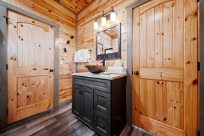 Ein Holzkamin mit Waschbecken, Spiegel und Handtuchhalter.