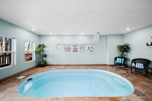An indoor swimming pool with a tiled floor, clear signage, and two wicker chairs. - Glorious Wooden Cabin with Swimming Pool in Pigeon Forge, Tennessee (Pigeon Forge)