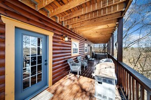 Eine Holzhütte mit Veranda, Grill und Gartenmöbeln.