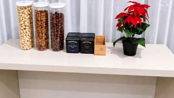 A white table with containers of nuts, two boxes labeled 'Twinings Earl Grey Tea' and 'Twinings Assam Tea,' and a potted red poinsettia plant.