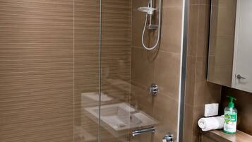 A modern bathroom with a glass-enclosed shower, a white bathtub, and a sink with a mirror above it.