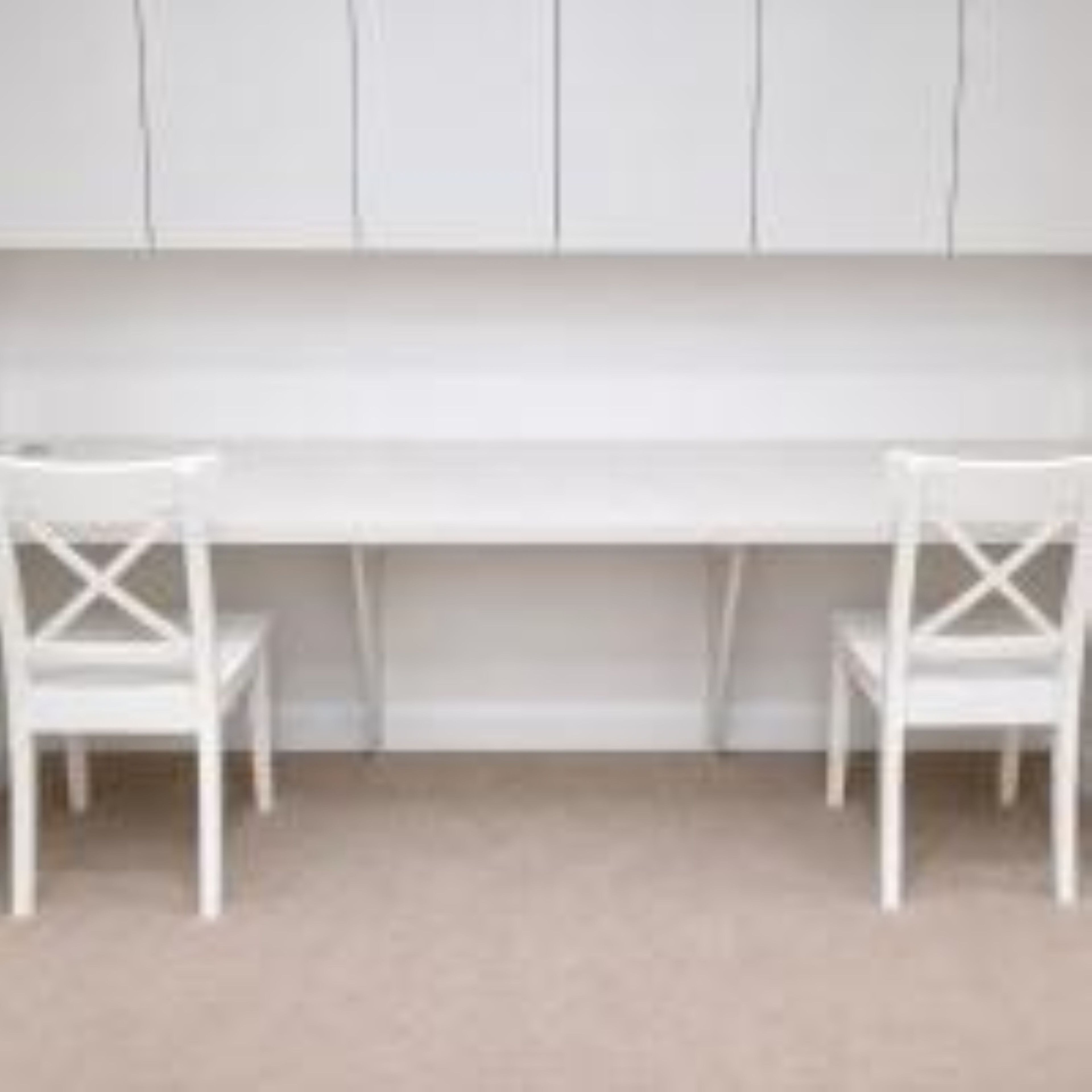 A room with a white desk and two white chairs.