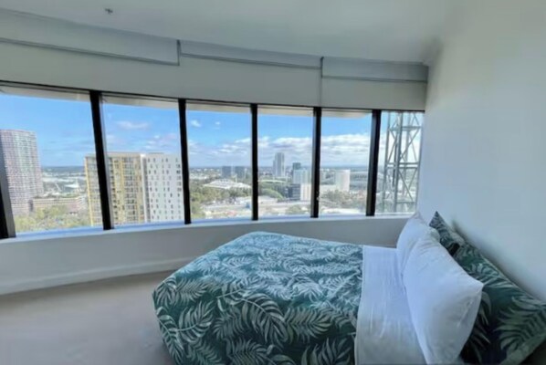A bedroom with a bed, large windows, and a view of the cityscape. - Sydney olympic park Free parking 08 (Sydney Olympic Park)