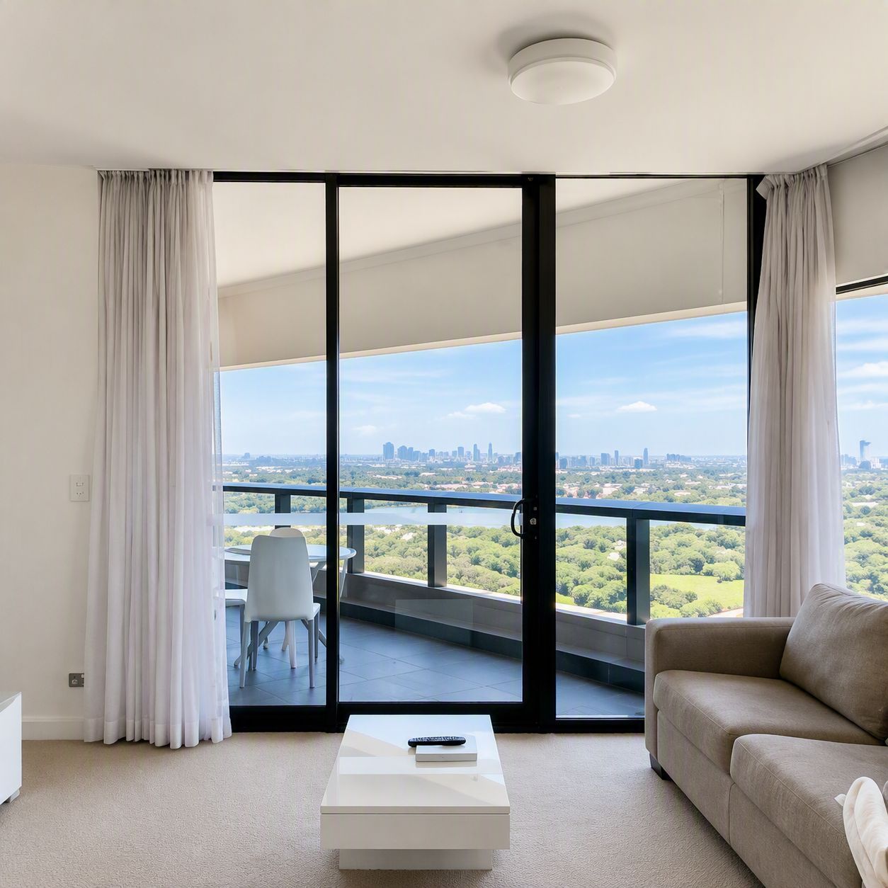 A modern living room with a sofa, a coffee table, and a view of a cityscape through large glass doors.
