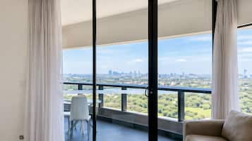 A modern living room with a sofa, a coffee table, and a view of a cityscape through large glass doors.