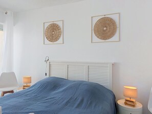 A bedroom with a bed, two wall-mounted lamps, and two framed wall art pieces. - Apartment Casino by Interhome (Lacanau)