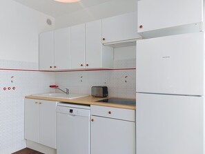 A modern kitchen with white cabinets, a dishwasher, a toaster, and a refrigerator. - Apartment Casino by Interhome (Lacanau)