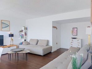 Ein modernes Wohnzimmer mit Sofa, Couchtisch, Bücherregal und Fernseher.