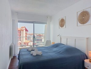 Ein Schlafzimmer mit einem großen Bett, Blick auf Gebäude und zwei Wandbildern.