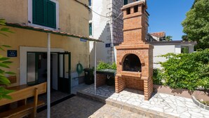 Um pátio com forno de tijolos, um banco e uma porta que dá para um edifício.