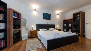 Quarto com cama, abajures, estante de livros, espelho e uma pintura na parede.