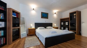 A bedroom with a bed, bedside lamps, a bookshelf, a mirror, and a painting on the wall. - House Antonia by Villas Guide (Opuzen)