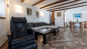 A living room with a leather chair, sofa, and a coffee table with a placemat. There is a wooden staircase leading to another room, and a dining area with a table and chairs. - House Antonia by Villas Guide (Opuzen)