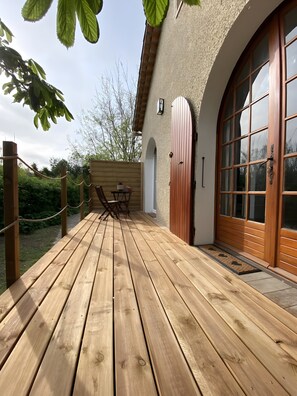 A wooden deck with a table and chairs, a wooden fence, and a building with large windows and a door.