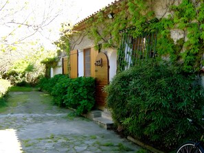 A stone pathway leading to a building with a wooden door and a metal gate.