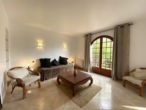 Ein Zimmer mit einem Bett, zwei Stühlen, einem Tisch und einem großen Fenster mit Vorhängen.
