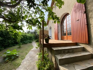 A house with a stone pathway leading to a wooden deck and a red door.