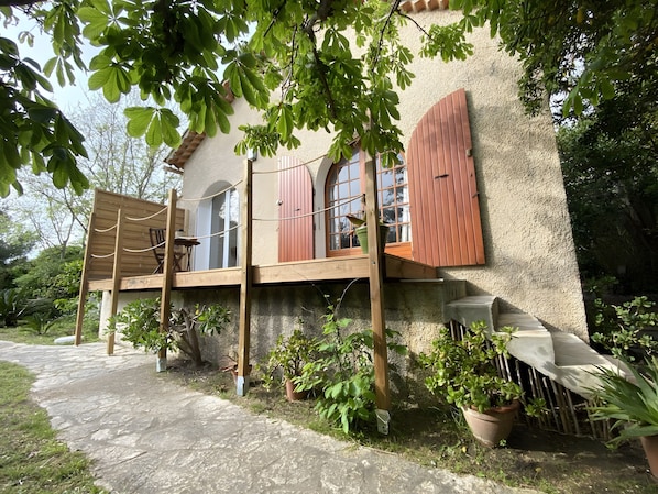 A house with a wooden deck, potted plants, and a stone pathway.