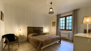 A bedroom with a bed, a chair, a desk, a lamp, a window, and a radiator.
