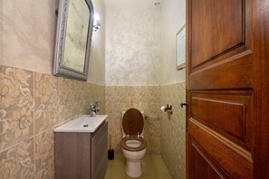 Een badkamer met een houten toilet, een wastafel en een spiegel.