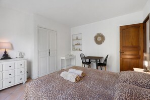 Un dormitorio con cama, escritorio, silla, armario y puerta.