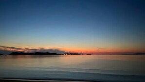 A calm body of water with a clear horizon and distant landforms.