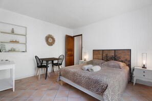 A bedroom with a bed, a desk, chairs, and a small table.