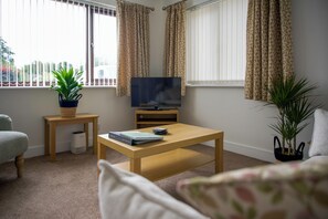 A living room with a television, a coffee table, a sofa, and two potted plants. - Peaceful Lake District home, near Ennerdale Water (Kirkland)