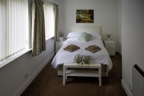 A bedroom with a bed, bedside tables, a clock, and a painting on the wall. - Peaceful Lake District home, near Ennerdale Water (Kirkland)