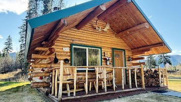A wooden cabin with a porch, a window, and a door.