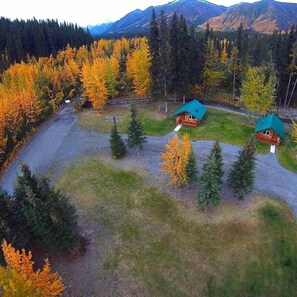 A lodge with three cabins, surrounded by a forest and mountains.