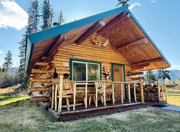 A wooden cabin with a porch, a window, and a door.