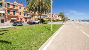 A street with parked cars, a palm tree, and buildings with balconies. - Ospedaletti by the Sea by Wonderful Italy (Ospedaletti)
