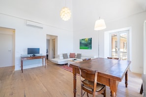 Ein geräumiger Wohnbereich mit Esstisch aus Holz, einer Couch und einem Fernseher.
