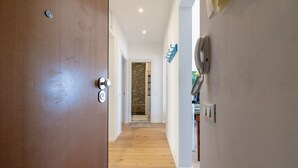 A hallway with a wooden door, a stone wall, and a white wall with a blue sign. - Ospedaletti by the Sea by Wonderful Italy (Ospedaletti)