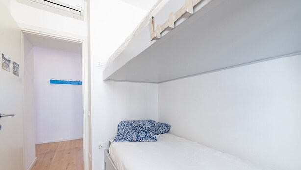 A bunk bed room with a door, a blue towel rack, and a patterned pillow. - Ospedaletti by the Sea by Wonderful Italy (Ospedaletti)