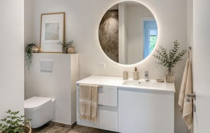 Ein modernes Badezimmer mit Toilette, Waschbecken, Spiegel und Handtuchhalter.