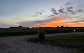 Ländliche Landschaft mit einem Feldweg, Feldern und einem Sonnenuntergang.