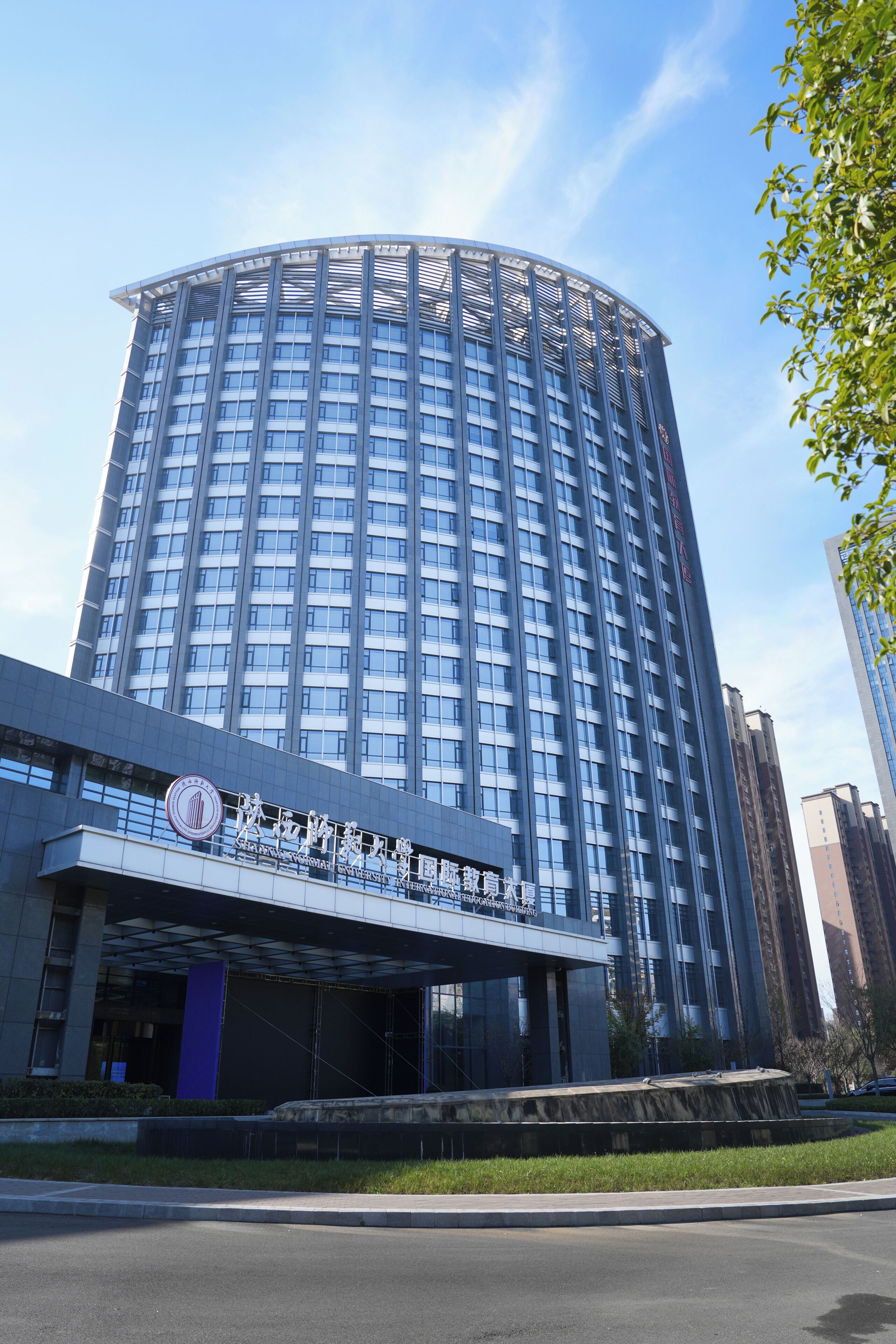 A modern building with a curved facade, large windows, and a prominent entrance with signage.
