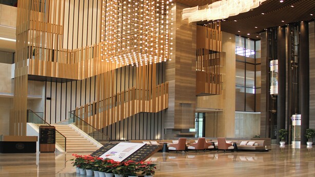 A modern lobby with a central staircase, seating area, and a unique light installation. - Shaanxi Normal University International Education Building (Xi'an)