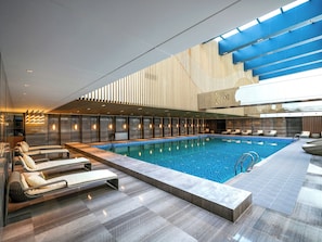 Una piscina interior moderna con sillones de descanso y un diseño contemporáneo.
