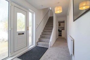 Un escalier menant à un palier où se trouvent une porte et un radiateur au mur.