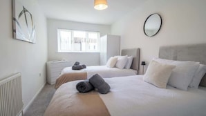 Une chambre d’hôtel avec deux lits, une fenêtre, un radiateur, un bureau et un miroir.