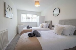 Une chambre d’hôtel avec deux lits, une fenêtre, un radiateur, un bureau et un miroir.