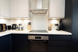 A modern kitchen with a built-in oven, a coffee maker, and a kettle. - Church House by Guestz (Filton)