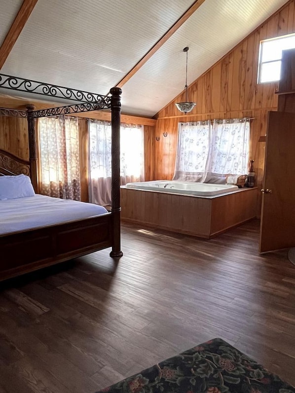 Une chambre à coucher avec un lit à baldaquin, une banquette intégrée avec un lavabo, des murs en bois et un plafond en pente.