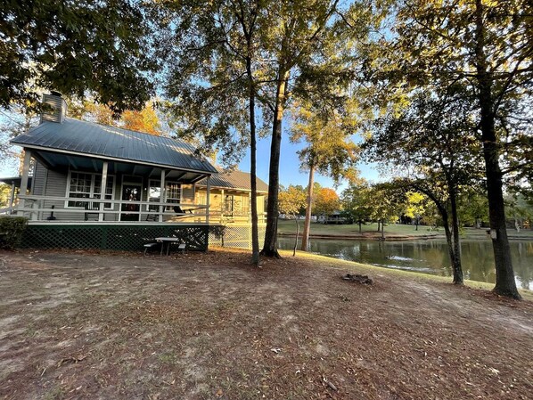 A lakeside building with a covered porch, surrounded by trees and a body of water.
