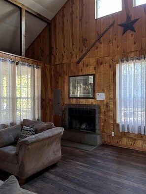 A wooden-paneled room with a fireplace, a sofa, and curtains.