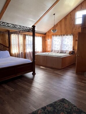 Un dormitorio con cama con dosel, una banqueta empotrada con lavabo, paredes de madera y techo inclinado.